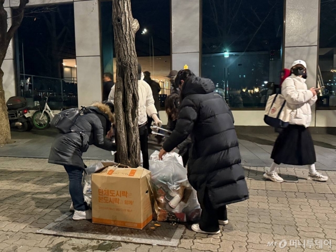 지난7일 밤 서울 여의도 국회의사당 근처에서 집회 참여자들이 쓰레기를 수거하며 집회 장소를 치우고 있다. /사진=김선아 기자 