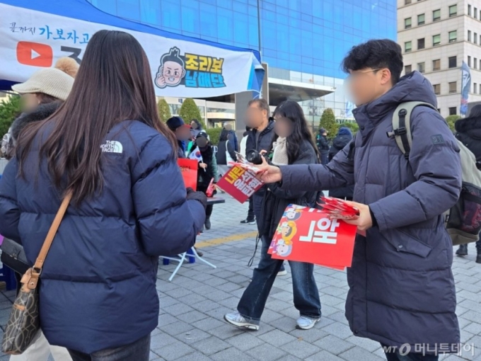 지난 7일 오후 1시45분쯤 서울 영등포구 여의도동 촛불집회에 참석한 시민들이 손피켓과 핫팩을 나눠주고 있다. 한낮에도 추운 날씨에 두꺼운 패딩과 목도리 등으로 무장한 모습이다./사진 이혜수 기자 