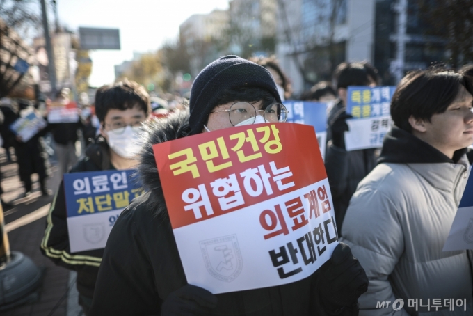 [서울=뉴시스] 정병혁 기자 = 8일 서울 종로구 대학로에서 열린 서울대병원 전공의협의회 비상대책위원회 ‘젊은 의사 의료계엄 규탄 집회’에서 사직 전공의를 비롯한 젊은 의사들이 피켓을 들고 있다. 2024.12.08. jhope@newsis.com /사진=정병혁